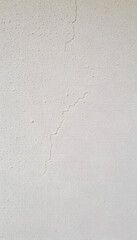 A textured stucco wall in beige, featuring natural cracks and imperfections that add depth and character. This surface brings warmth and a rustic charm to any interior space