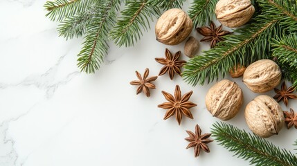 Xmas decoration including natural green fir branches composed with walnuts and aromatic anise stars on white marble surface.