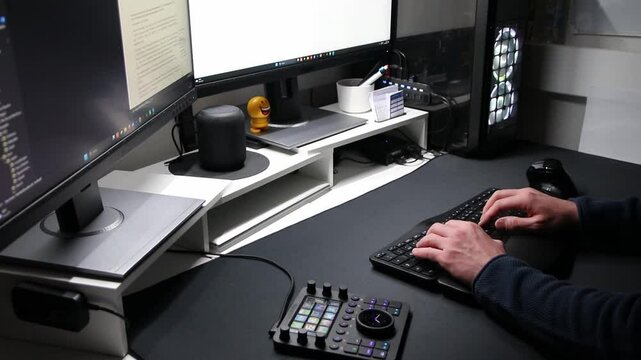 European man using ergonomic workplace equipment for login and using apps in two monitors setup to work from home office or as freelancer with modern technology setup and special devices for streaming