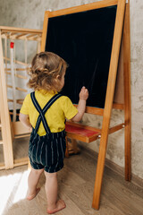 A little boy stands by a wooden plank at home