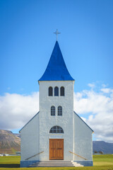Front view of the Hofsós Church in Iceland, featuring a white facade and blue roof against a clear sky.