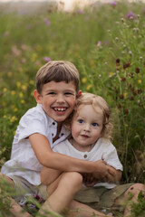 Two brothers of a boy are sitting in a field hugging