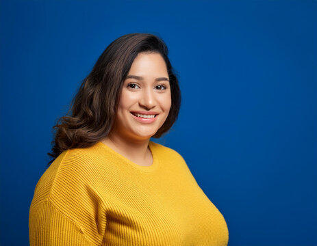 Studio Portrait of Beautiful Happy Young Woman Smiling Against Blue Studio Background Confidently