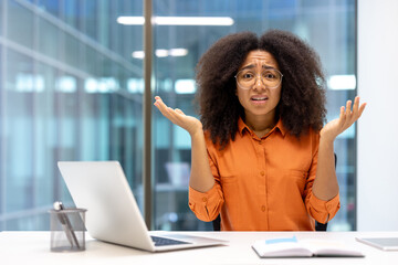 Confused woman at desk expressing uncertainty in office setting with laptop