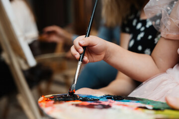 Fototapeta premium A child explores creativity by painting on a palette in an art class