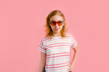 Emotional blonde teen girl in sparkle sunglasses laughing to camera on pink background