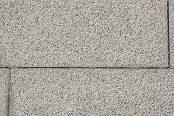 Rough surface of wall made of granite or cement blocks. Gray color textured background with even joints between bricks. Urban environment building design. 