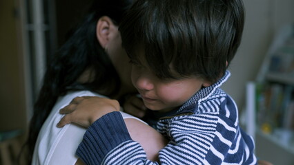 Obraz premium Young boy feeling sad while being comforted by his mother. child rests on her shoulder, showing visible distress and seeking comfort in a calm home