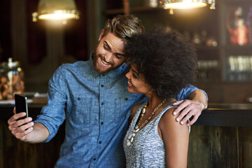 Hug, selfie and couple in cafe, smile and bonding together with happiness, love and romance. Interracial, man and woman with embrace, smartphone and mobile user with memory, picture and restaurant