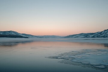 A Frozen River Landscape with Snowy Mountains and a Pink Sunset Sky