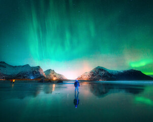 Beautiful Aurora borealis and man on the beach at night. Lofoten islands, Norway. Northern Lights....