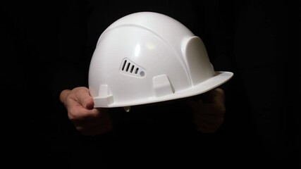 A white construction safety helmet held firmly in hands, representing workplace safety culture