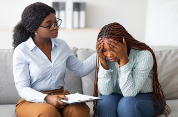 Upset black lady with nervous breakdown consulting psychologist, having session with counselor at...