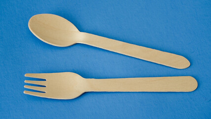 A wooden spoon and fork lie on a blue surface