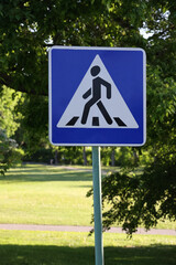 A Crosswalk Sign In A Park Setting Conveys Safety And Navigation. The Sign Against A Lush, Green Backdrop Is Perfect For Themes Of Safety, Urban Planning, And Outdoor Environments..