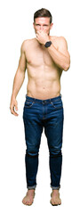 Handsome shirtless man showing nude chest smelling something stinky and disgusting, intolerable...