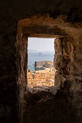 View of Dubrovnik harbor and old town rooftops through a stone window