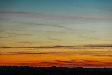 A vibrant sunset showcasing a gradient of colors from deep blue to orange and red near the horizon. The clear sky creates a tranquil atmosphere with a subtle transition of hues