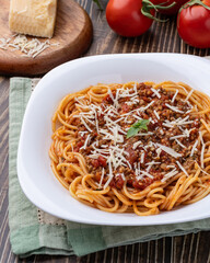 Spaghetti pasta on a plate with bolognese sauce, basil and parmesan cheese