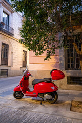 Red scooter parked on a quiet street with historic buildings in Madrid - Portrait