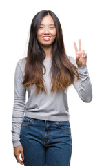 Obraz premium Young asian woman over isolated background smiling with happy face winking at the camera doing victory sign. Number two.