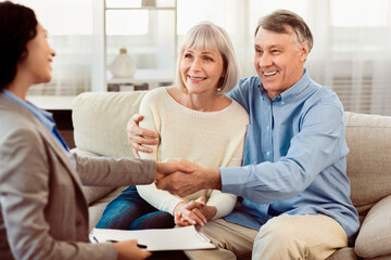 Real Deal. Real estate agent giving handshake to smiling elderly couple after successful agreement, free space