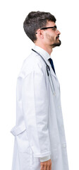 Obraz premium Young doctor man wearing hospital coat over isolated background looking to side, relax profile pose with natural face with confident smile.
