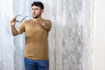 man holding glasses with vision problems