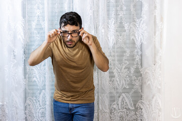 man adjusting glasses and leaning forward against white background