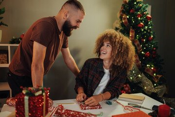 Happy couple wrapping christmas gifts at home