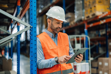 Warehouse manager using digital tablet checking inventory in logistics center