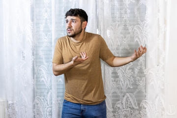 Man gesturing confusion with arms out on a white background
