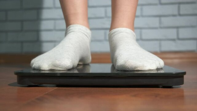 Teen legs on electronic scales. A view of girl legs on the smart home scale on the floor.