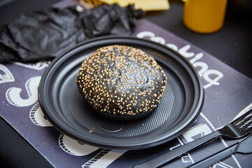 Black burger on a black plate