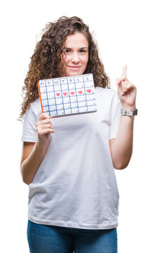 Young brunette girl holding menstruation calendar over isolated background surprised with an idea or question pointing finger with happy face, number one
