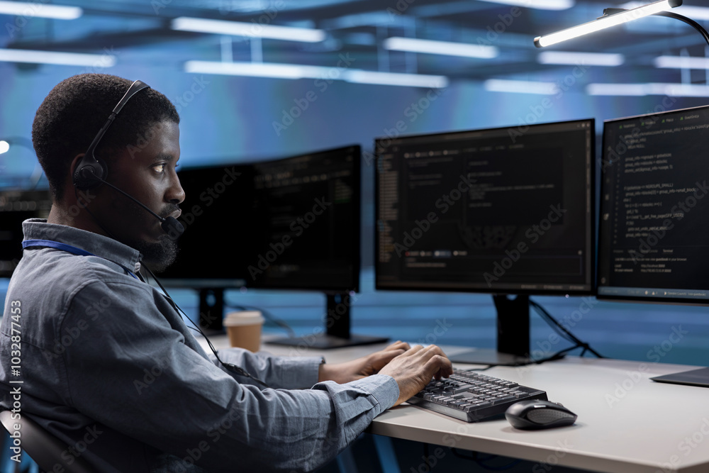 Poster engineer in data center managing call center tasks, speaking into headset while monitoring multiple 