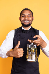 Catering employee showing a thumbs up gesture in studio, presenting his approval and content emotions on camera. Young restaurant waiter gives a like sign, professionalism.