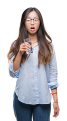 Young asian woman drinking a glass of water over isolated background scared in shock with a surprise face, afraid and excited with fear expression