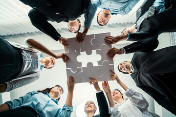 Multiethnic business people holding jigsaw pieces and merge them together as effective solution...