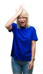 Young beautiful blonde woman wearing glasses over isolated background surprised with hand on head...