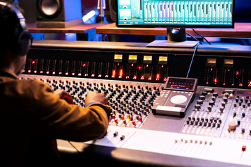 African american sound designer operates control room mixer and audio software for editing new...