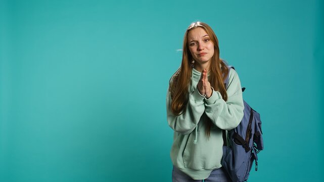 Woman doing begging hand gesture, in ardent need of favor from friend, isolated over studio background. Young girl doing please gesturing, requesting assistance, camera B