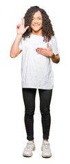 Fototapeta premium Young beautiful woman with curly hair wearing white t-shirt Swearing with hand on chest and fingers, making a loyalty promise oath