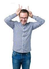 Fototapeta premium Handsome middle age elegant senior man wearing glasses over isolated background Posing funny and crazy with fingers on head as bunny ears, smiling cheerful
