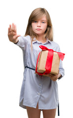 Young blonde toddler holding a present with open hand doing stop sign with serious and confident expression, defense gesture