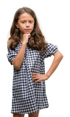 Brunette hispanic girl wearing black and white dress serious face thinking about question, very confused idea