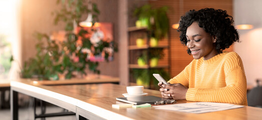 Positive afro girl chatting with clients of friends, working at cafe, empty space