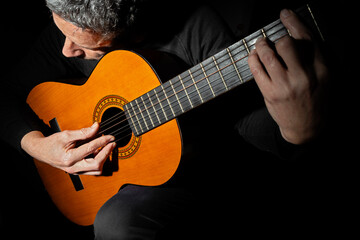 CLOSE UP OF A MAN PLAYING CLASSICAL GUITAR.