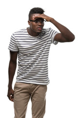 Fototapeta premium Young african american man wearing glasses and navy t-shirt very happy and smiling looking far away with hand over head. Searching concept.