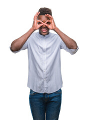Fototapeta premium Young african american man over isolated background doing ok gesture like binoculars sticking tongue out, eyes looking through fingers. Crazy expression.